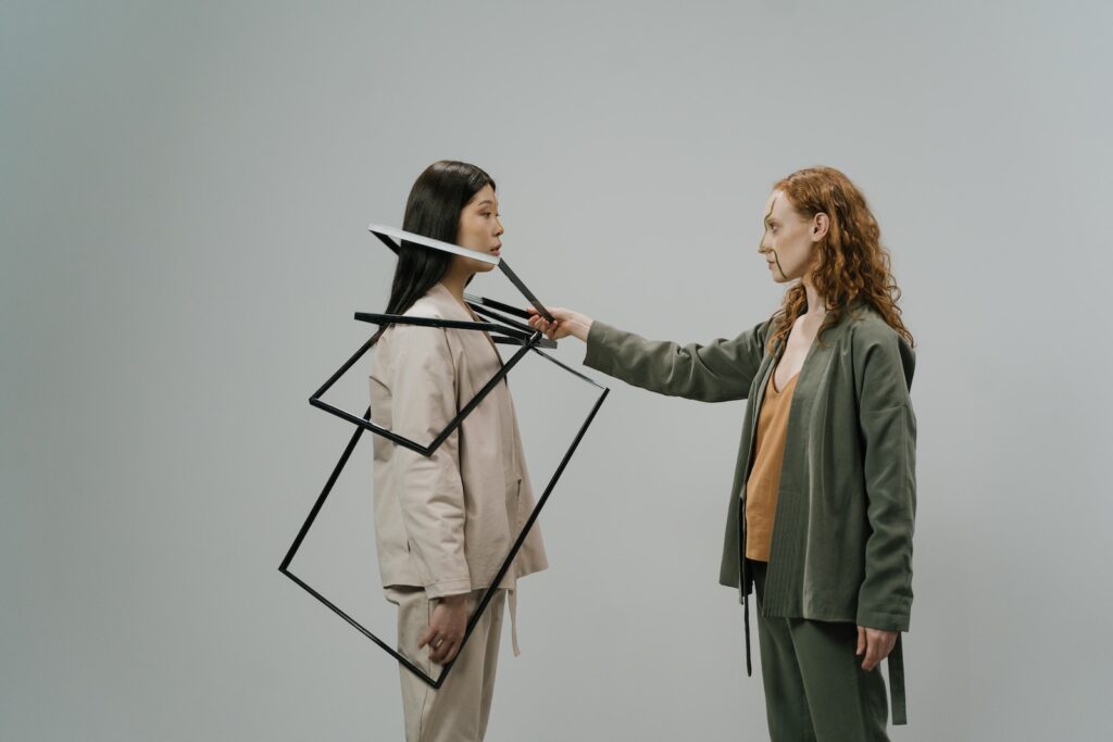 到底是吹什麼牛?2分鐘帶你了解吹牛規則 3 Young female model in green costume and beige top putting empty photo frames on shoulders of other female model wearing light beige jacket and trousers