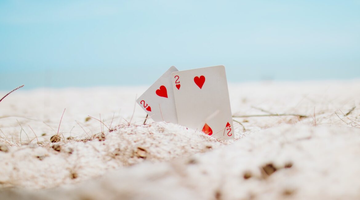 white and red heart playing card on white sand during daytime