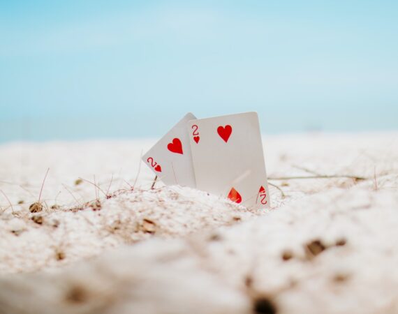 white and red heart playing card on white sand during daytime