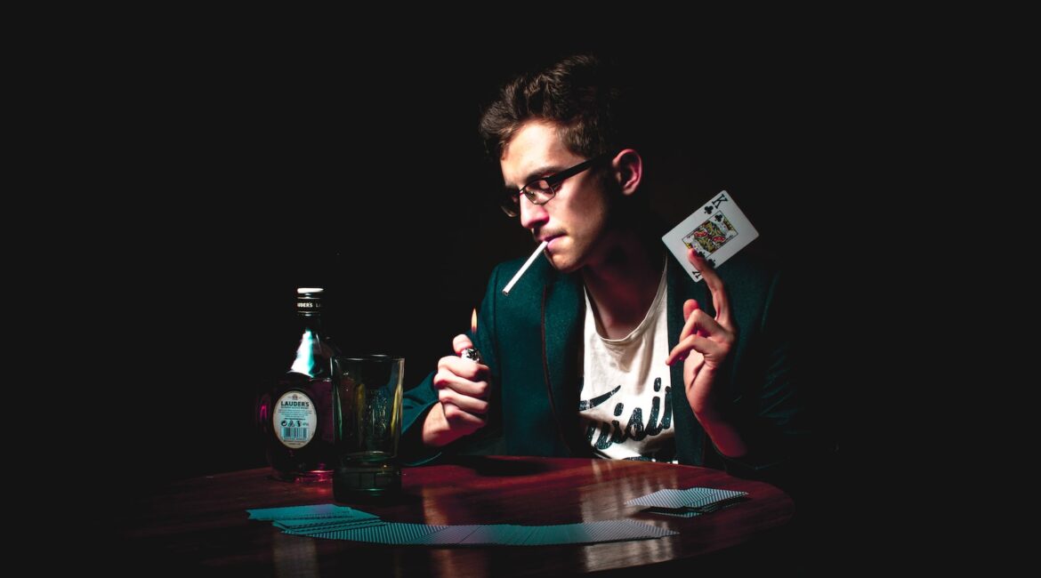 man lighting cigarette while holding playing card